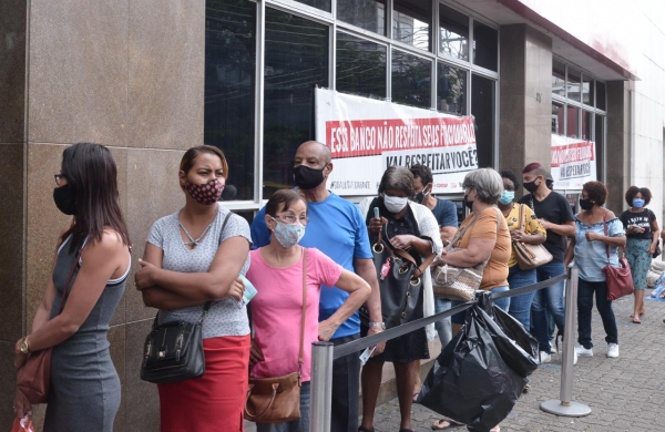 DENÚNCIA - Uma multidão do lado fora, tomando chuva, na agência da Rua Augusto Vasconcelos, em Campo Grande. As demissões pioram o atendimento e o Bradesco se nega a atender a população nas agências