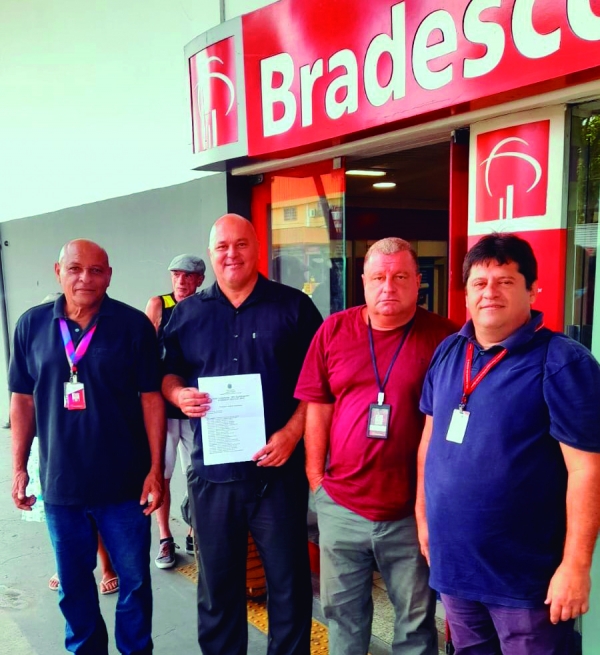 O bancário reintegrado Ivanildo Sebastião de Medeiros, da agência Ceasa do Bradesco, de posse do documento de reintegração, ao lado de Arlensen Tadeu (E), Sérgio Menezes e Edelson Figueiredo 