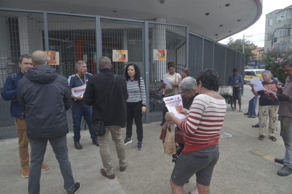 Populares l&ecirc;em o panfleto e a edi&ccedil;&atilde;o do Jornal Banc&aacute;rio durante o protesto do Sindicato do Rio, em Bonsucesso, contra as demiss&otilde;es no Ita&uacute; 